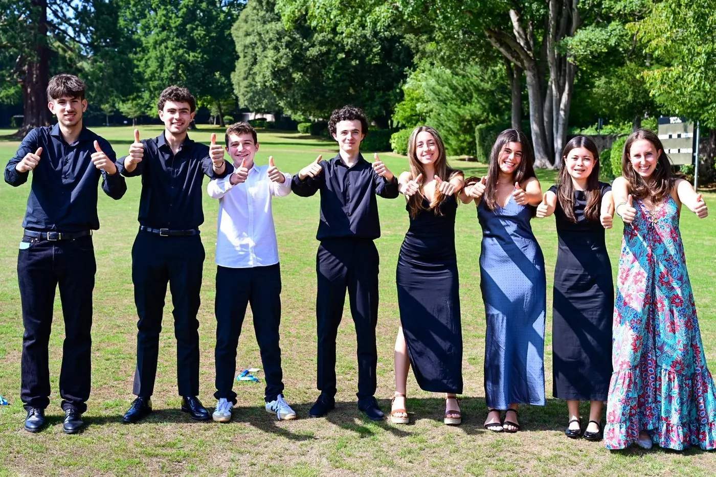 A group of students in concert dress giving a thumbs up after performing